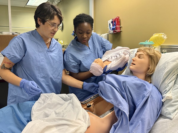 Nursing students assisting manikin in labor