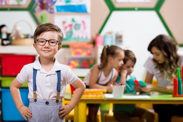 Preschool kid smiling in front of classmates 